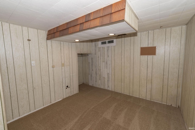 basement featuring carpet flooring and wood walls