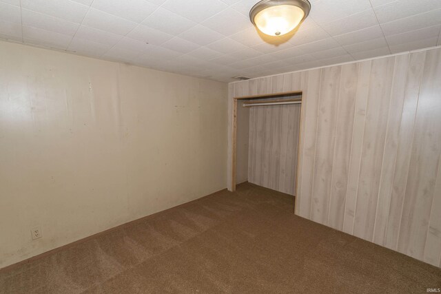 carpeted empty room with wooden walls