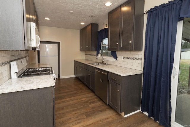 kitchen featuring sink, dark wood-type flooring, stainless steel appliances, tasteful backsplash, and dark brown cabinets