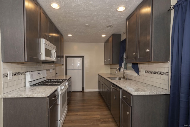 kitchen featuring decorative backsplash, a textured ceiling, white appliances, sink, and dark hardwood / wood-style floors