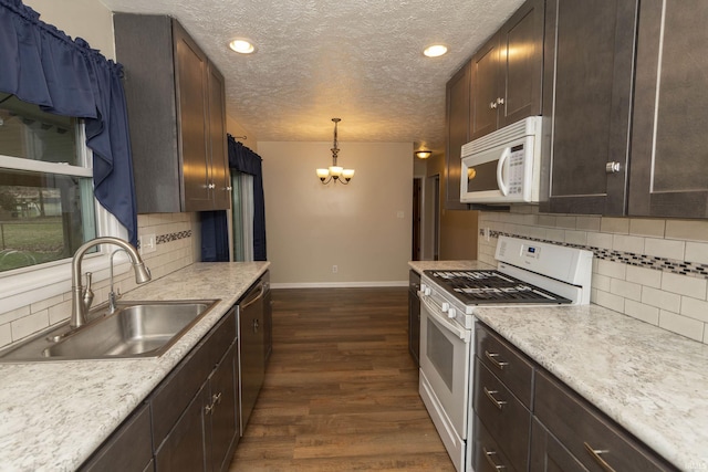 kitchen with sink, hanging light fixtures, dark wood-type flooring, a chandelier, and white appliances