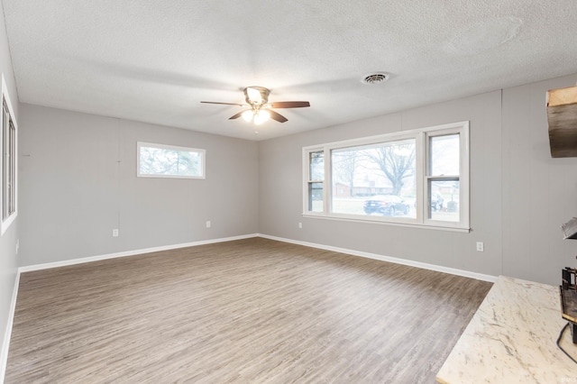 unfurnished living room with a wealth of natural light, wood-type flooring, and a textured ceiling