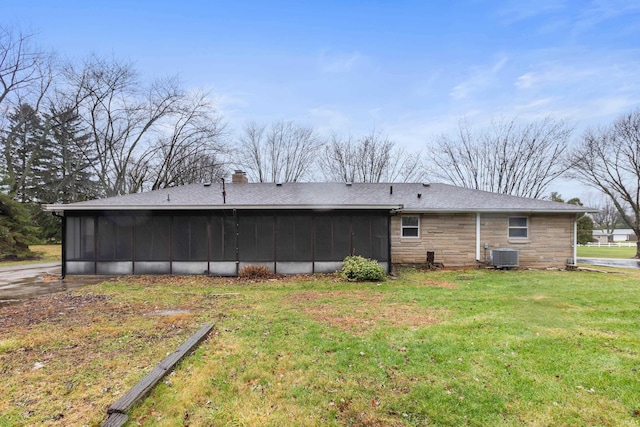 back of property with central AC, a sunroom, and a yard