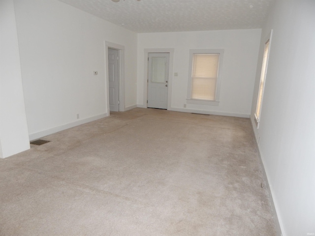 unfurnished room featuring light carpet and a textured ceiling