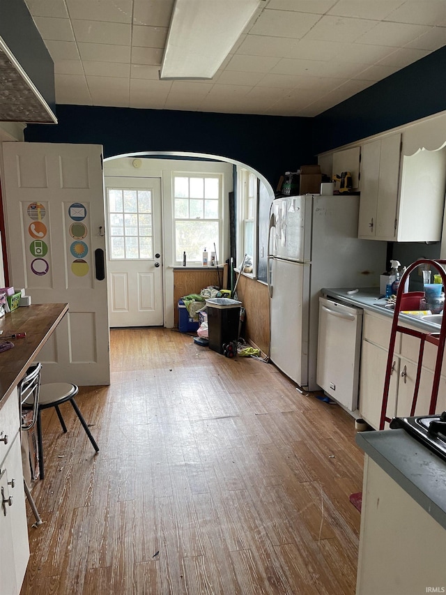 kitchen with stainless steel dishwasher, white cabinets, sink, and light hardwood / wood-style flooring