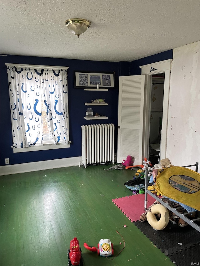 dining room featuring radiator, wood-type flooring, and a textured ceiling