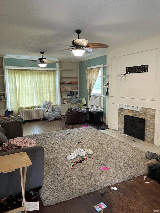 living room featuring radiator, ornamental molding, cooling unit, hardwood / wood-style flooring, and a fireplace