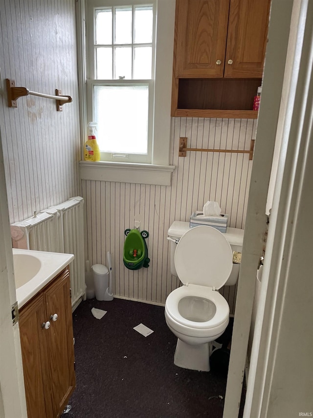 bathroom featuring vanity, toilet, radiator heating unit, and wooden walls