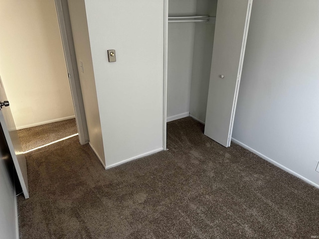 unfurnished bedroom with a closet and dark colored carpet