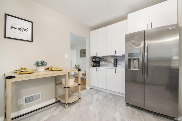 kitchen with stainless steel fridge with ice dispenser, backsplash, and white cabinetry