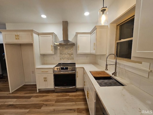 kitchen with sink, dark wood-type flooring, wall chimney range hood, stainless steel range oven, and decorative light fixtures