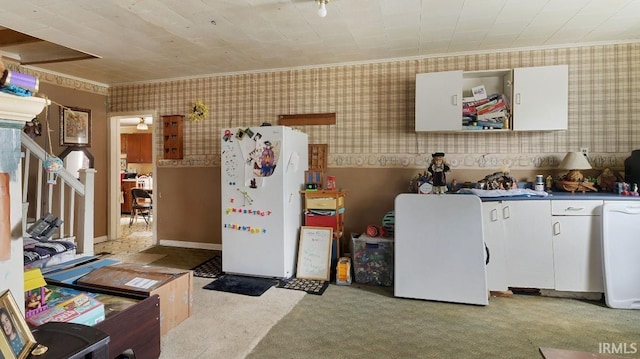 kitchen with white cabinets, white refrigerator, light colored carpet, and crown molding