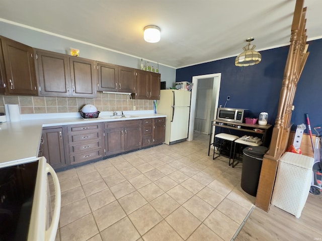 kitchen featuring white appliances, sink, decorative backsplash, light tile patterned floors, and dark brown cabinets