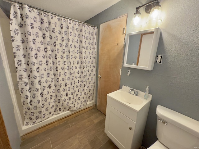 bathroom with hardwood / wood-style floors, vanity, a shower with shower curtain, toilet, and a textured ceiling