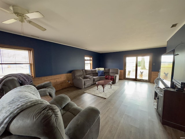 living room featuring ceiling fan, wooden walls, and light hardwood / wood-style flooring