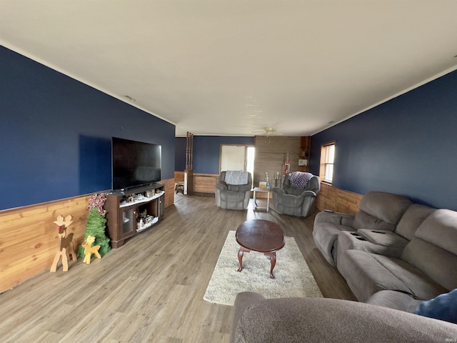 living room with hardwood / wood-style floors, ceiling fan, and wooden walls