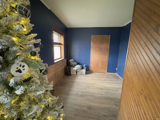 unfurnished room with light wood-type flooring and wooden walls