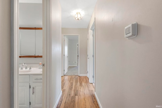 corridor with sink and light hardwood / wood-style flooring