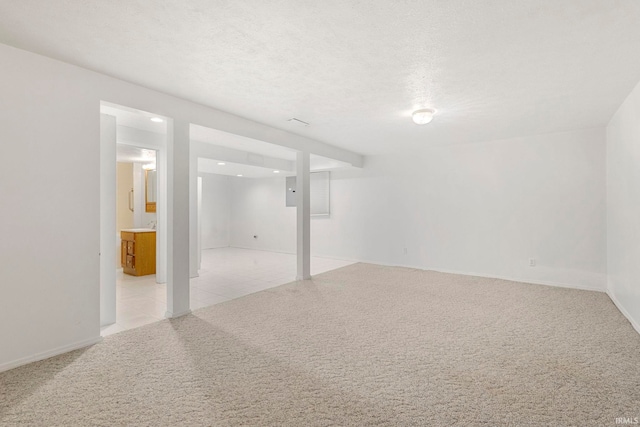 spare room featuring a textured ceiling and light carpet