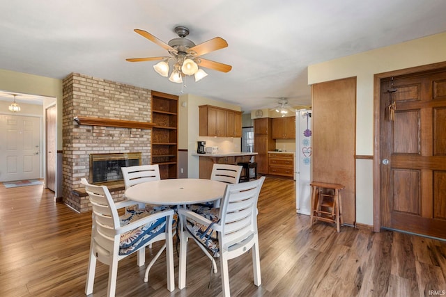 dining area with a fireplace, hardwood / wood-style flooring, built in features, and ceiling fan