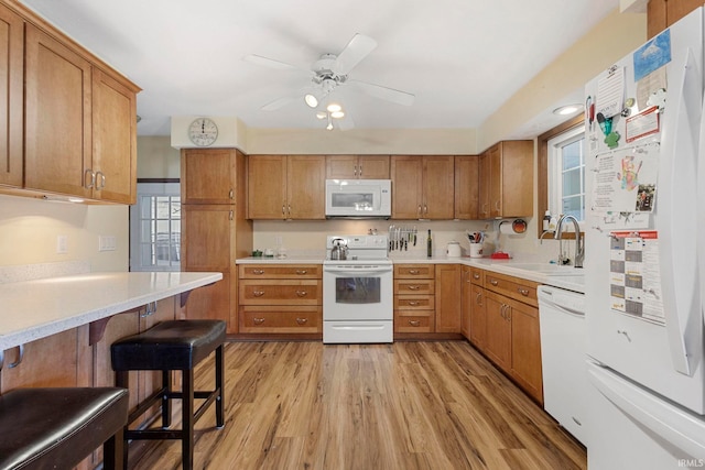 kitchen with plenty of natural light, light hardwood / wood-style floors, white appliances, and sink