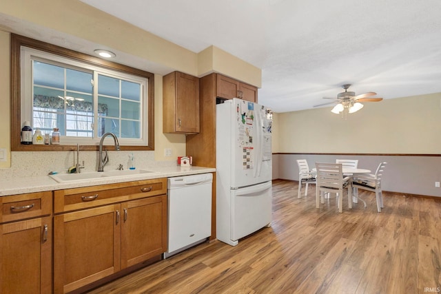 kitchen featuring ceiling fan, sink, light hardwood / wood-style floors, and white appliances