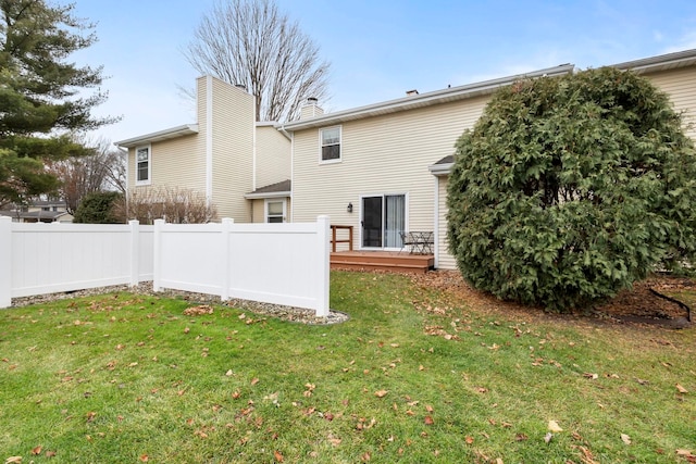 rear view of property featuring a lawn and a deck