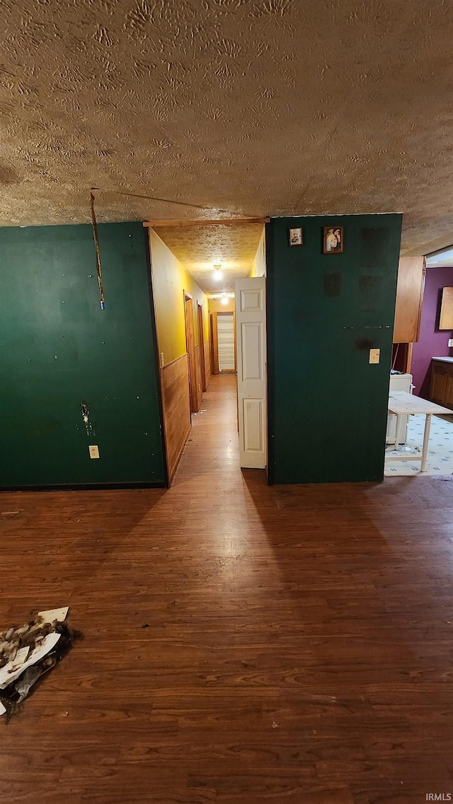 hall with wood-type flooring and a textured ceiling