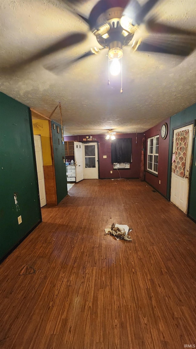 unfurnished living room featuring dark wood-type flooring and a textured ceiling