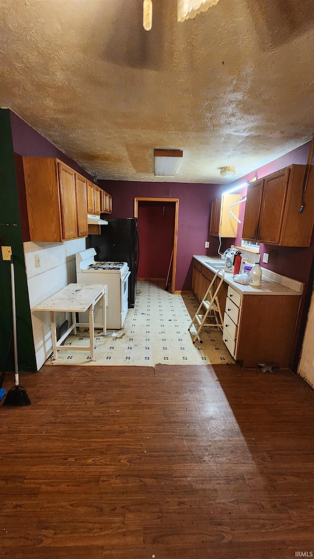 kitchen featuring sink, white gas range, a textured ceiling, and light hardwood / wood-style flooring