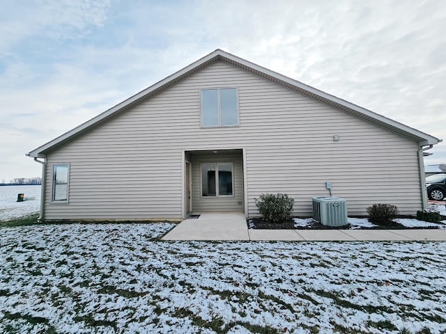 snow covered house with cooling unit and a patio