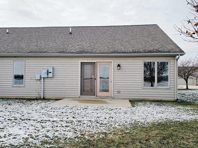 snow covered rear of property with a patio area