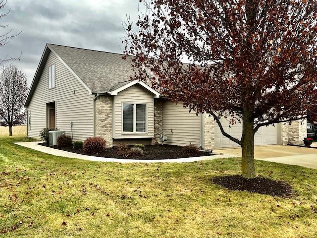 view of side of property with a lawn, cooling unit, and a garage