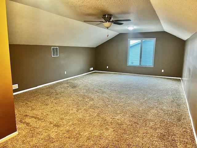 additional living space featuring carpet flooring, ceiling fan, lofted ceiling, and a textured ceiling