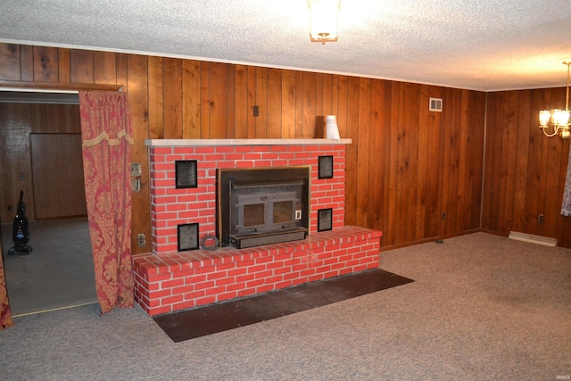 living room featuring wood walls, carpet floors, a textured ceiling, and an inviting chandelier