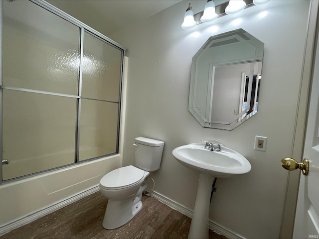 full bathroom featuring sink, toilet, wood-type flooring, and bath / shower combo with glass door