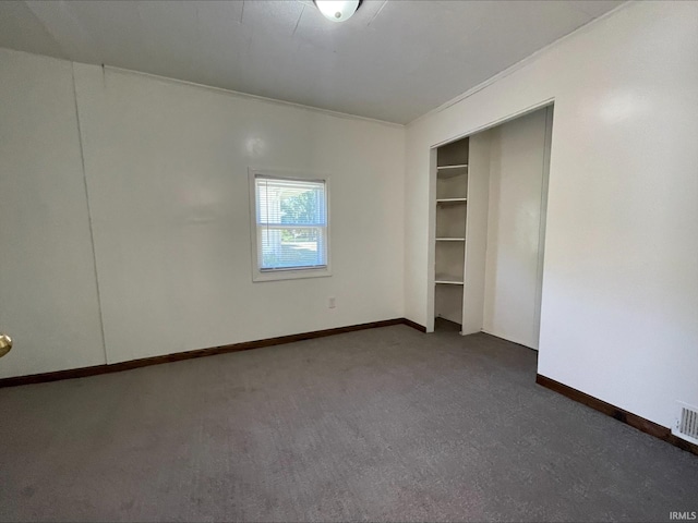 empty room with ornamental molding and dark colored carpet