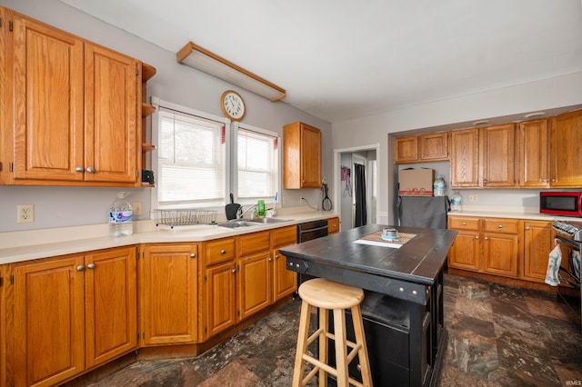 kitchen with a center island, sink, stainless steel fridge, black dishwasher, and a kitchen bar