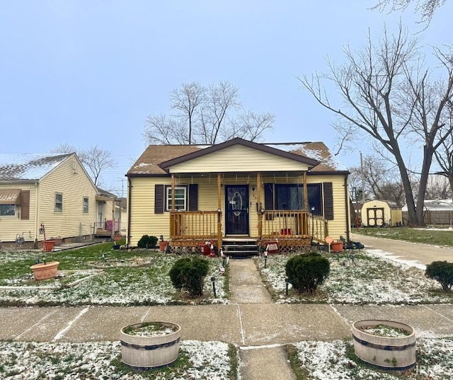 bungalow-style home with a storage unit and covered porch