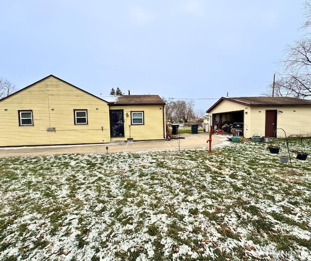 snow covered property featuring an outbuilding and a garage