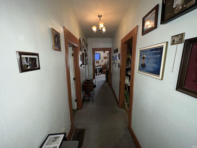 hallway with light carpet and a notable chandelier