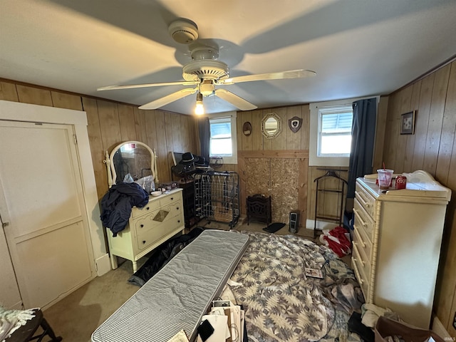 bedroom featuring ceiling fan, a wood stove, wooden walls, and multiple windows