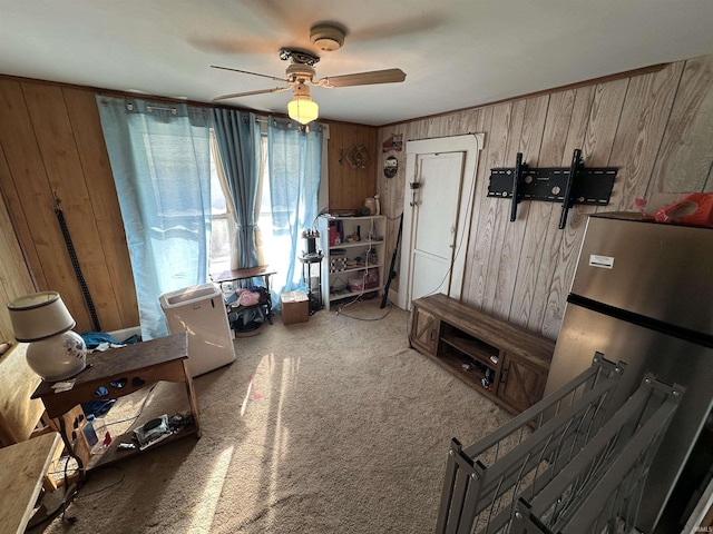 interior space with carpet floors, wood walls, and ceiling fan