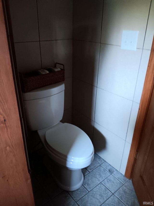 bathroom with tile patterned floors, toilet, and tile walls