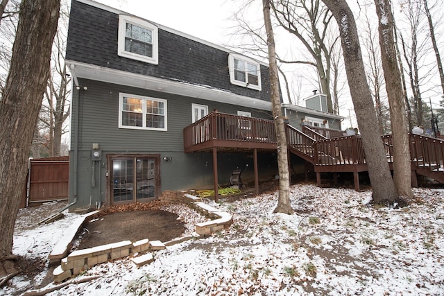 snow covered back of property featuring a deck