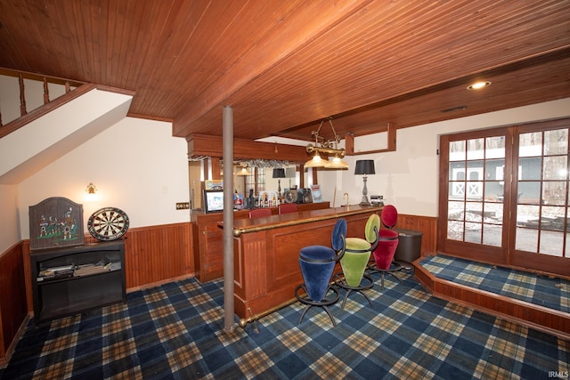 bar with pendant lighting, wood walls, wood ceiling, and vaulted ceiling