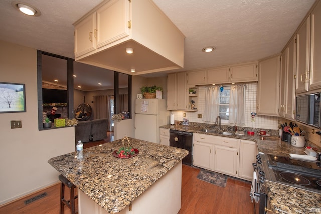 kitchen with hardwood / wood-style floors, a breakfast bar, white refrigerator, electric stove, and black dishwasher