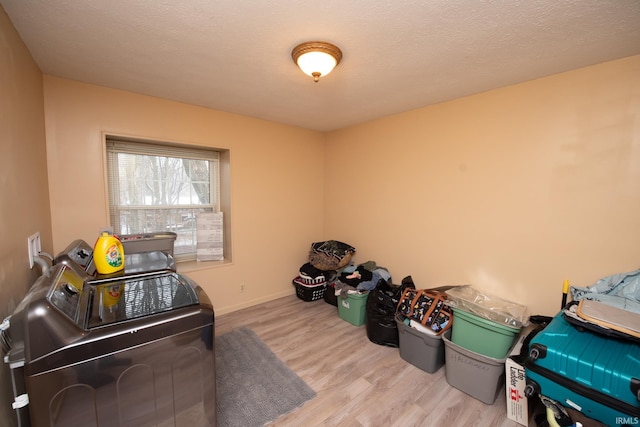 laundry area featuring independent washer and dryer, a textured ceiling, and light hardwood / wood-style flooring