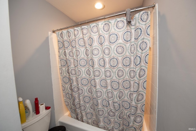 bathroom featuring shower / bathtub combination with curtain and toilet