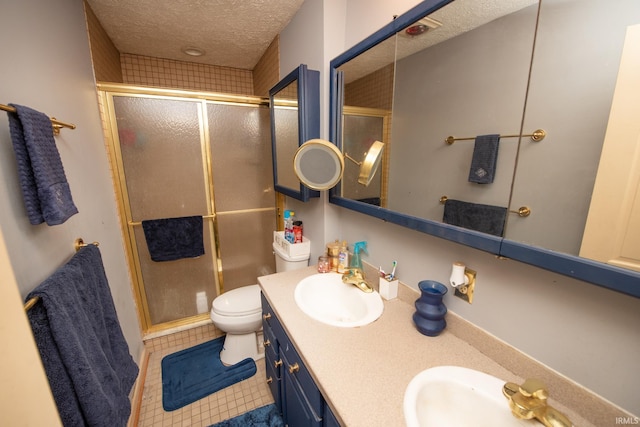 bathroom with vanity, tile patterned floors, toilet, a textured ceiling, and a shower with shower door